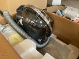 un aspirateur noir et argenté rangé dans un carton