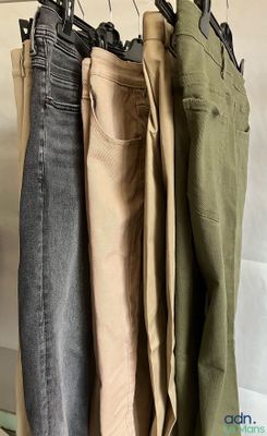 three pairs of jeans hanging on a rack in a room