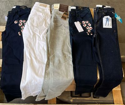 trois paires de jeans pour femmes suspendues à un portant devant un mur