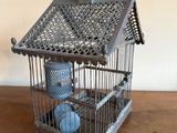 une cage à oiseaux posée sur une table, avec un oiseau à l'intérieur