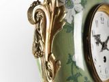 a clock hanging from a chain with flowers on it