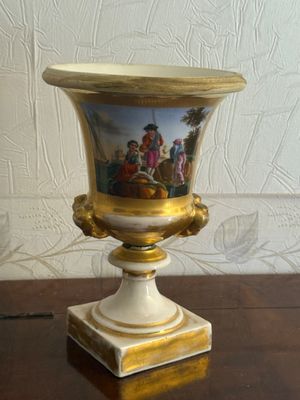 a vase with a painting on it sitting on a table