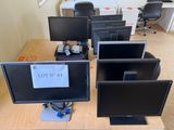 quatre écrans d'ordinateur posés sur un bureau, avec beaucoup de câbles