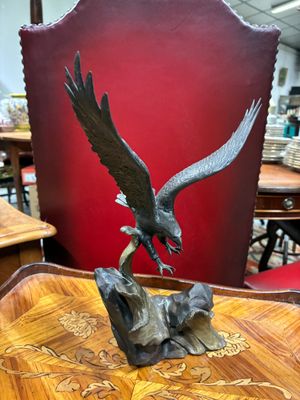 une photo représentant une statue d'aigle posée sur une table en bois