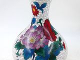un vase avec des fleurs peintes dessus, posé sur une table