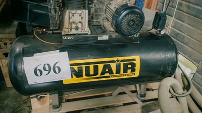 un compresseur d'air noir posé sur une palette dans un garage