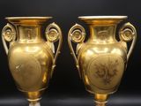 deux vases en or posés l'un sur l'autre sur une surface noire