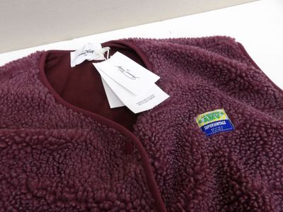 purple flee jacket with a tag on it sitting on a white surface