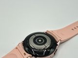 the watch has a pink strap around it and is on a white surface