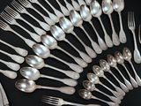 un grand nombre de cuillères et de fourchettes en argent disposées sur une table