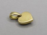 a close up of a gold heart charm on a gray surface