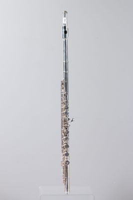 a silver flute on a clear stand against a gray background