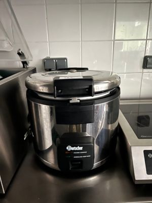 une mijoteuse argentée et noire posée sur une cuisinière