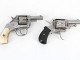 pair of old revolvers on a white surface with a wooden handle