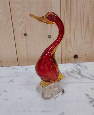 un oiseau en verre rouge posé sur une table en marbre