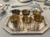 a silver tray with five cups on it and spoons