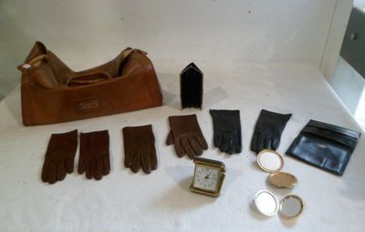 a lot of gloves, a purse, a watch, and other items laid out on a table