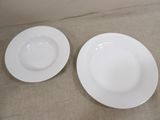 two white plates sitting on a table next to each other