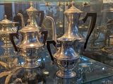 de nombreux vases en argent posés sur une table en verre dans une vitrine
