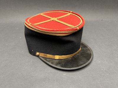 uniform hat with red and gold trim on a gray surface