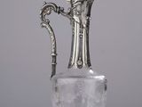 un vase ancien en verre plaqué argent, muni d'une anse et posé sur un socle