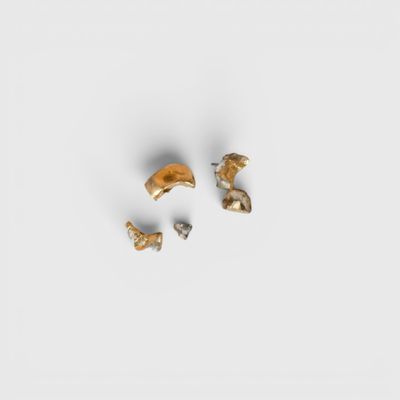 une paire de boucles d'oreilles en or et en argent posées sur une surface blanche