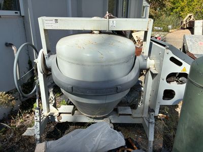 une bétonnière garée dans la cour, à côté d'une poubelle