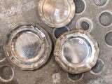 trois assiettes en argent posées sur un sol en béton