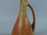 a brown and green vase sitting on a gray surface