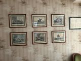 des tableaux accrochés au mur d'un salon où se trouve un fauteuil vert