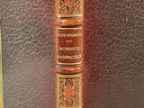 an old book with gold trim and a red cover on top of it