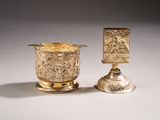two silver cups with designs on them sitting next to each other