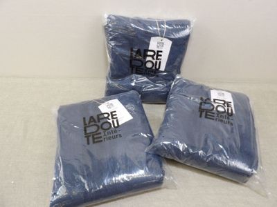 trois sacs remplis de chemises bleues posés sur une table blanche
