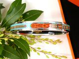 a bracelet that is sitting on a table next to a plant