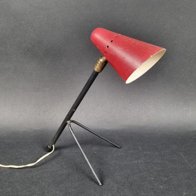 une image représentant une lampe rouge posée sur un trépied