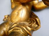 une statue en or représentant un bébé tenant un téléphone portable