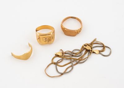 trois bagues en or et une paire de ciseaux posés sur une surface blanche