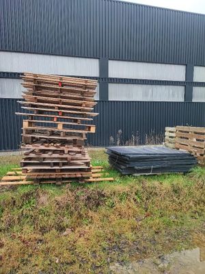un tas de bois posé dans l'herbe à côté d'un bâtiment