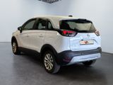 the rear end of a white car in a room with a ceiling fan