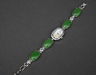 un gros plan d'une montre-bracelet ornée de pierres vertes