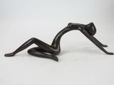 bronze sculpture of a woman laying on her back on a white surface