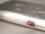 a silver case with a ruby stone in it