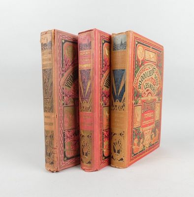 trois vieux livres sont empilés sur une surface blanche