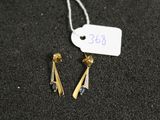 une paire de boucles d'oreilles posée sur une surface noire, avec une étiquette de prix