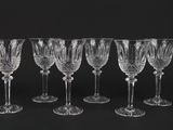 six crystal wine glasses lined up against a black background