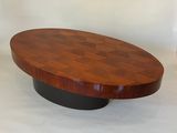 une table basse ovale avec un piètement noir et un plateau en bois