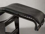the back of a black chair with a leather seat and foot rest