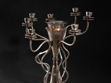 a silver candelier with five candles on a black background