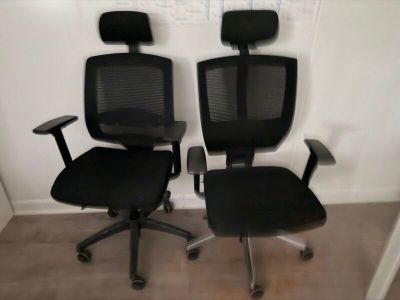 une paire de fauteuils de bureau noirs avec accoudoirs et dossiers dans une pièce