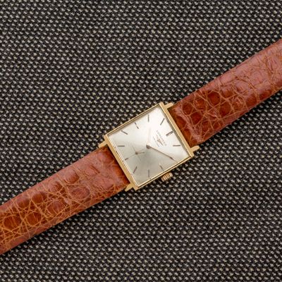 une photo d'une montre en or avec un bracelet en cuir marron